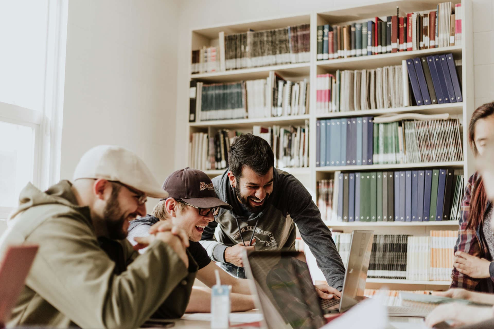 Three people laughing while doing work at a table.